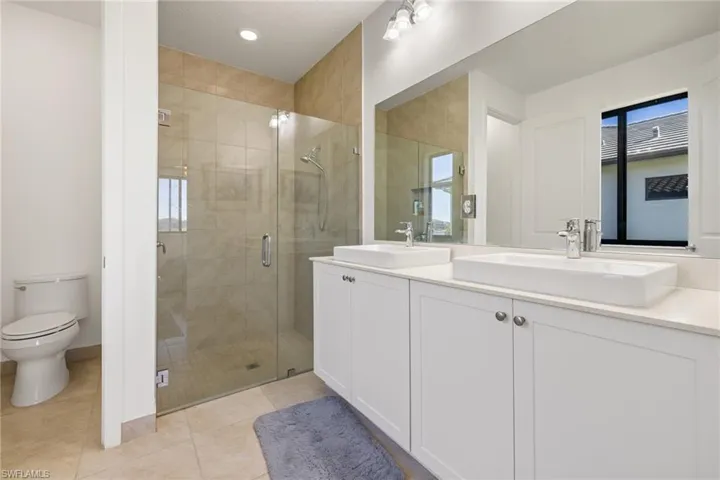 Bathroom with tile patterned floors, vanity, toilet, and walk in shower