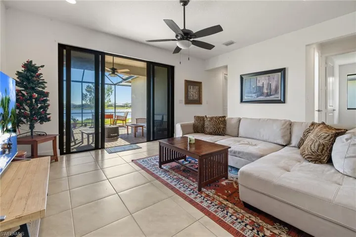 Living room featuring a water view, ceiling fan, and light tile patterned flooring