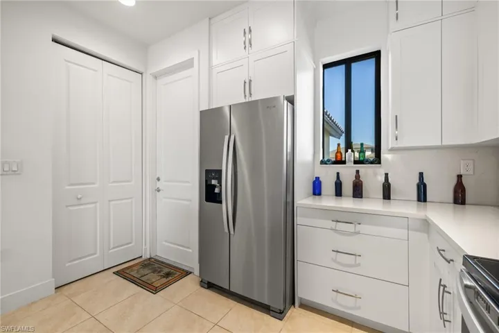 Kitchen with decorative backsplash, light tile patterned flooring, white cabinetry, and stainless steel appliances