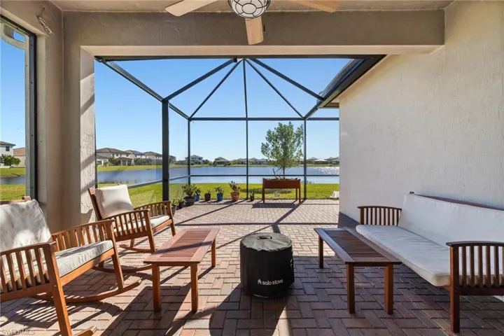 View of patio featuring a lanai, ceiling fan, a water view, and an outdoor hangout area