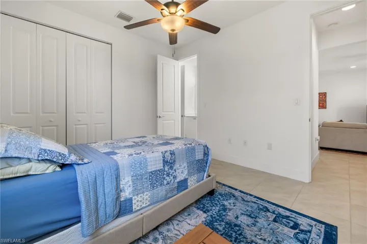 Tiled bedroom featuring ceiling fan and a closet
