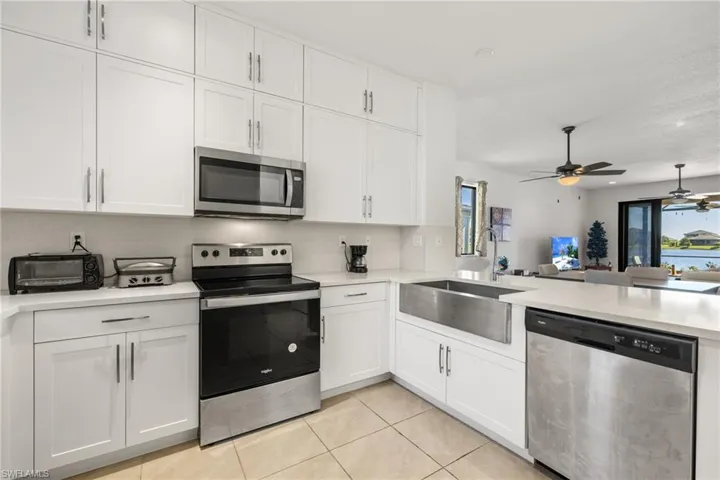 Kitchen with light tile patterned flooring, sink, white cabinetry, and stainless steel appliances