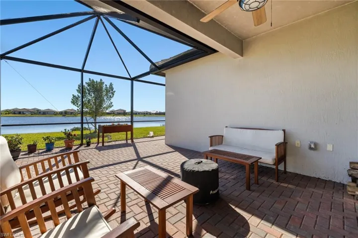 View of patio with glass enclosure, ceiling fan, and a water view