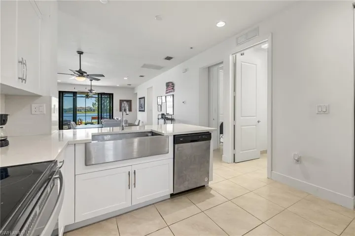 Kitchen featuring white cabinets, sink, stainless steel dishwasher, ceiling fan, and kitchen peninsula
