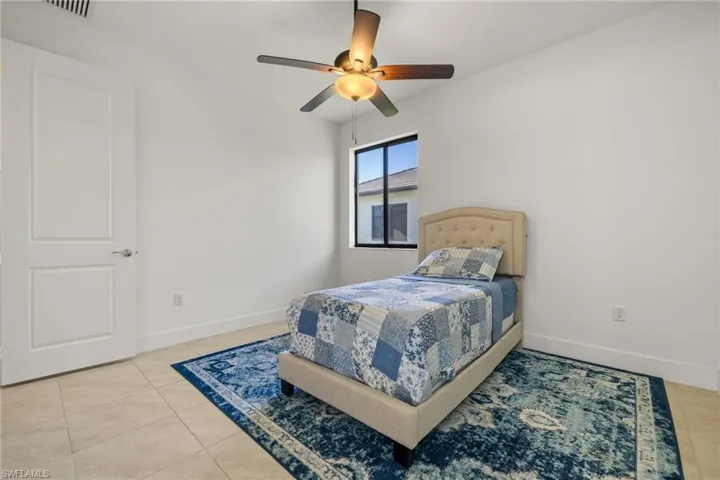 Tiled bedroom featuring ceiling fan