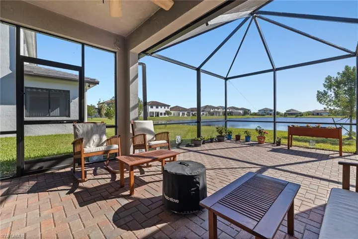 View of patio / terrace featuring a lanai, ceiling fan, and a water view