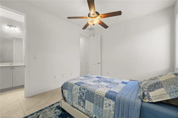Bedroom with ceiling fan, sink, light tile patterned floors, and ensuite bathroom