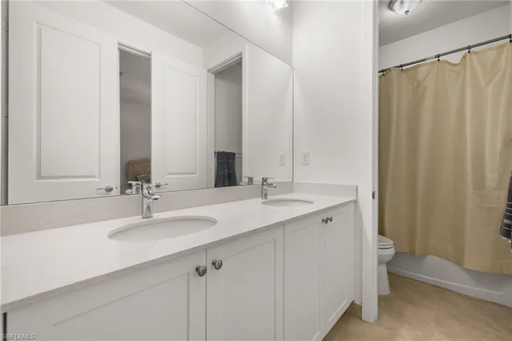 Full bathroom featuring shower / bath combo, vanity, a textured ceiling, tile patterned flooring, and toilet