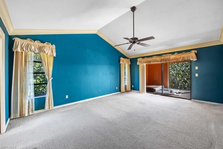 Unfurnished living room featuring crown molding, lofted ceiling, carpet flooring, and ceiling fan