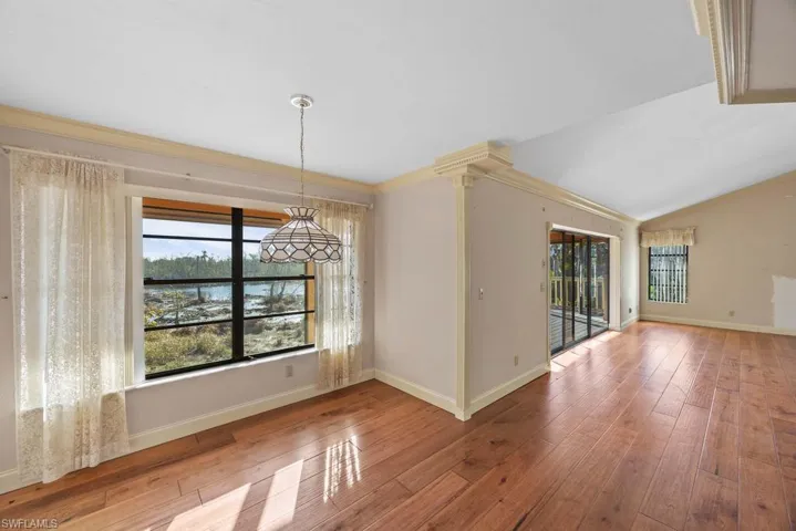 Unfurnished dining area featuring crown molding, wood-type flooring, and vaulted ceiling