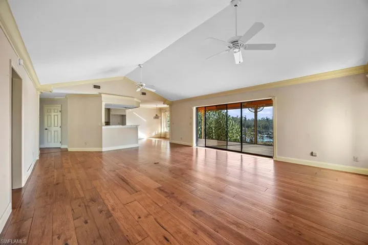 Unfurnished living room with vaulted ceiling, ornamental molding, ceiling fan, and light hardwood / wood-style flooring