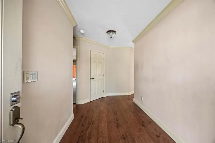 Hallway featuring ornamental molding and dark hardwood / wood-style floors