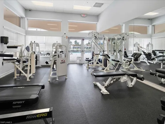 Fitness center featuring a variety of exercise equipment, full-height mirrored walls, and large windows with horizontal blinds