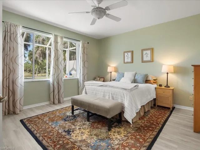 Spacious room featuring multiple windows, a ceiling fan, and light wood-finish flooring