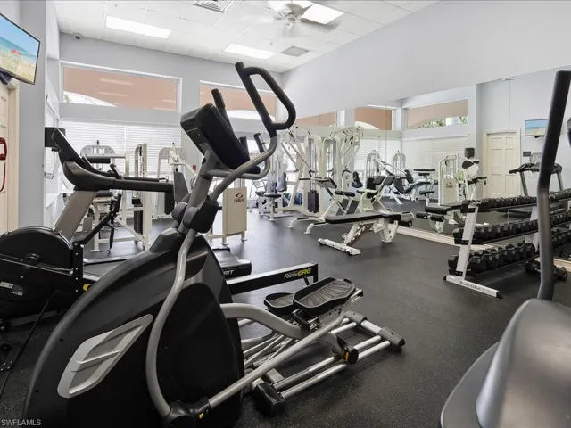 Fitness center featuring multiple exercise machines, weight racks, large wall mirrors, and recessed lighting