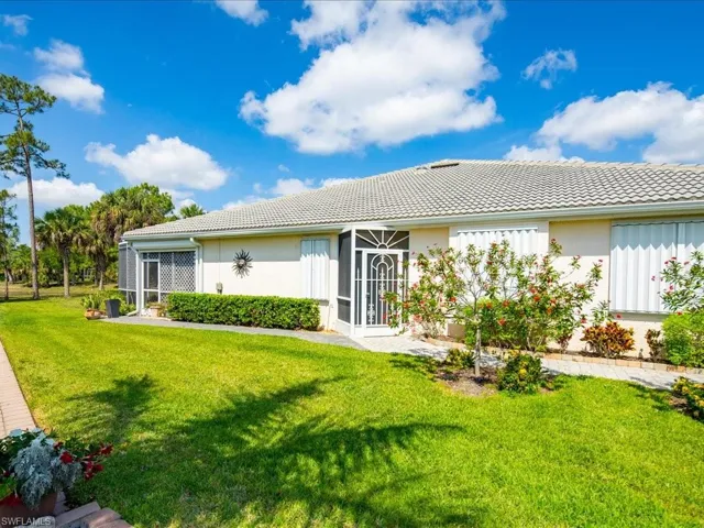 Exterior featuring a tiled roof, screened entry, and multiple windows with accordion shutters
