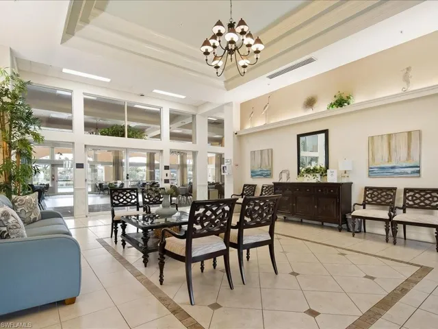 Spacious interior featuring a coffered ceiling with a chandelier, extensive window walls, and tiled flooring with decorative inlays