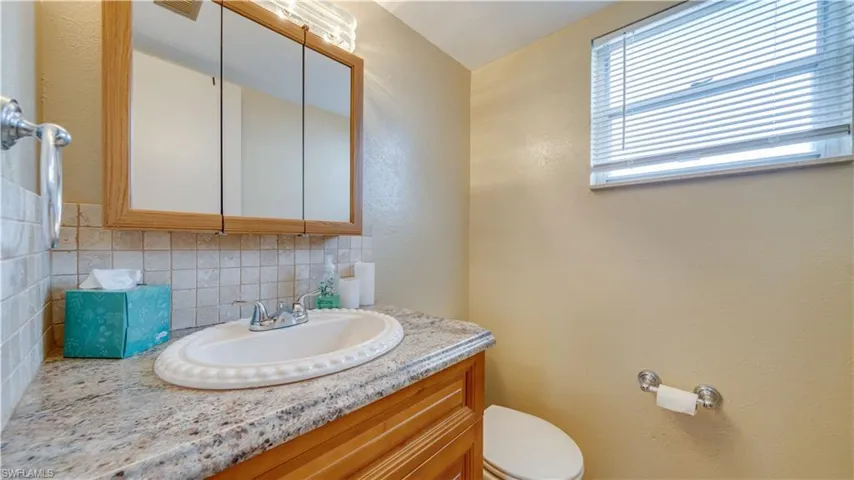 Half Bathroom with vanity, toilet, and tasteful backsplash