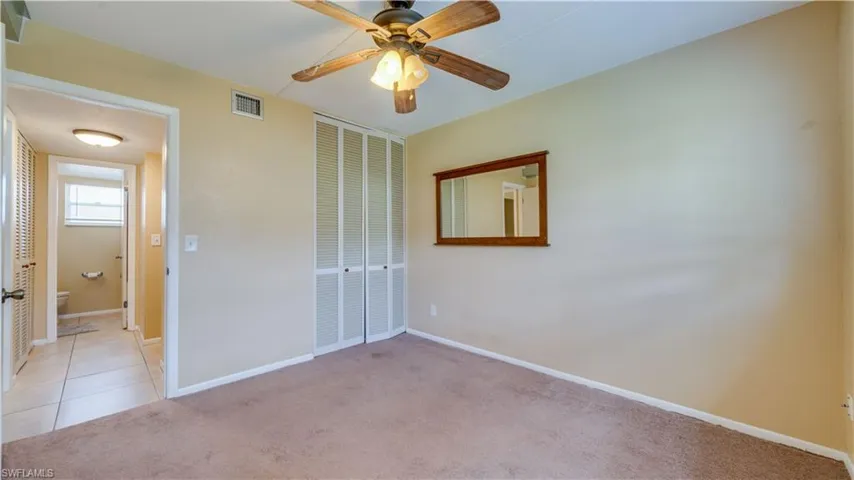 Unfurnished bedroom with light carpet, ceiling fan, and a closet