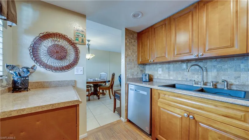Kitchen with pendant lighting, sink, stainless steel dishwasher, light hardwood / wood-style floors, and decorative backsplash