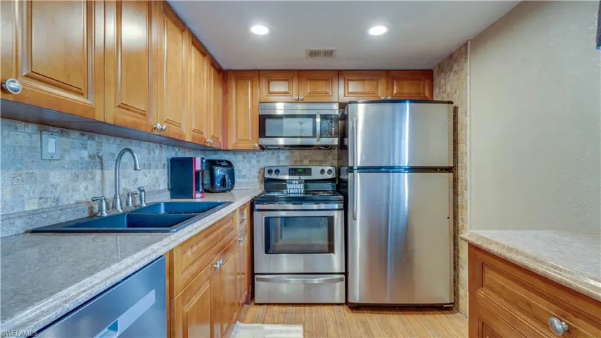 Kitchen featuring decorative backsplash, appliances with stainless steel finishes, sink, and light wood-type flooring