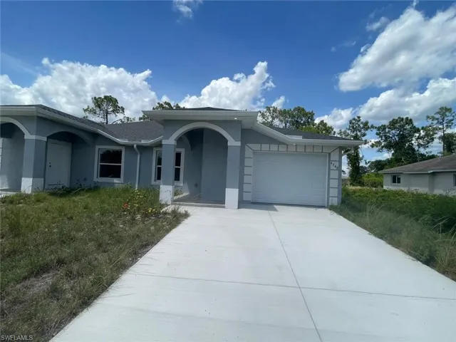 Single story home with stucco siding, an attached garage, and driveway