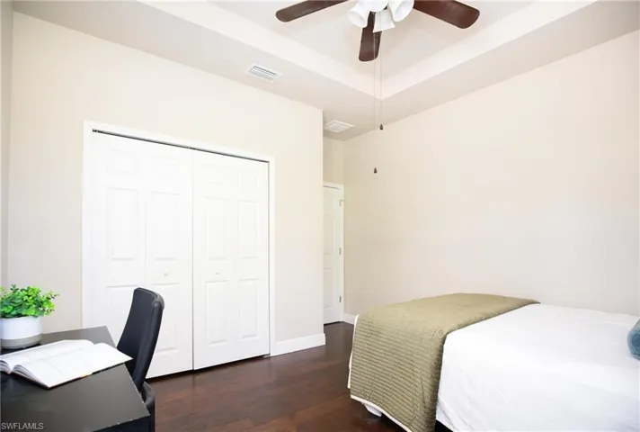 4th Bedroom featuring dark wood-type flooring, a closet, ceiling fan, and a raised ceiling