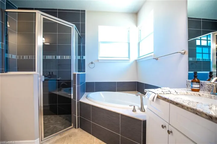 Bathroom with tile floors, vanity, and shower with separate bathtub