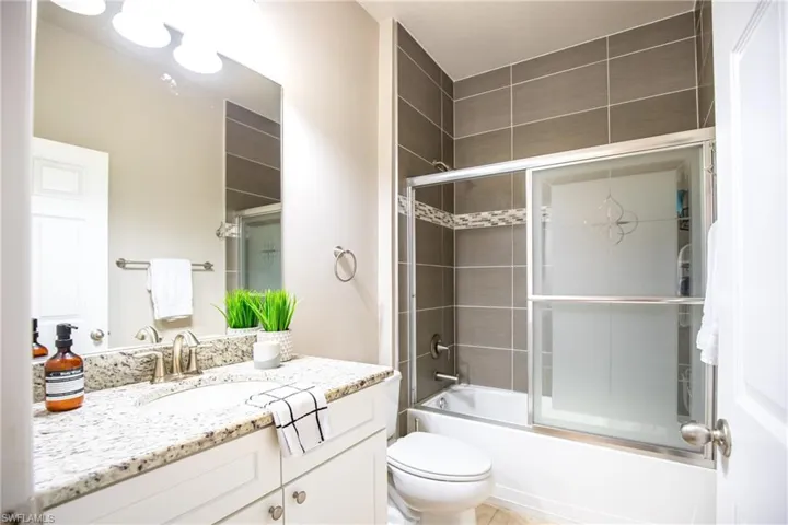 Guest Full bathroom featuring tile floors, bath / shower combo with glass door, vanity, and toilet