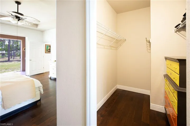 Spacious walk-in closet featuring dark hardwood floors
