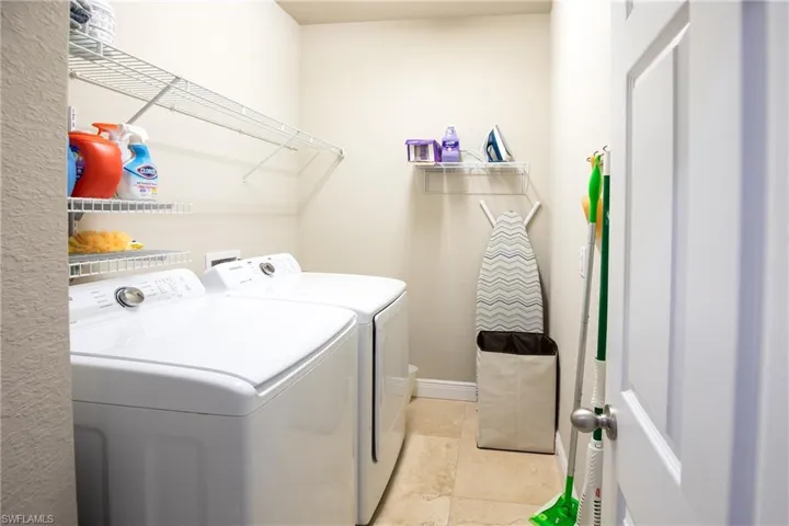 Laundry room featuring washer and dryer and light tile floors