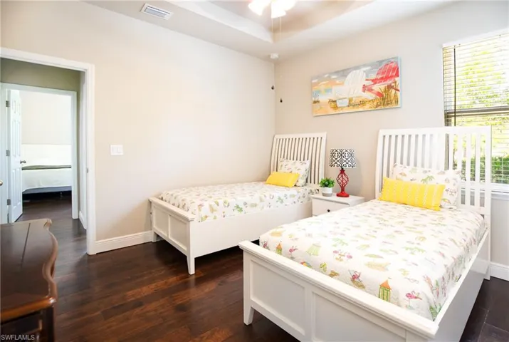 Bedroom featuring a tray ceiling, ceiling fan, and dark hardwood  flooring
