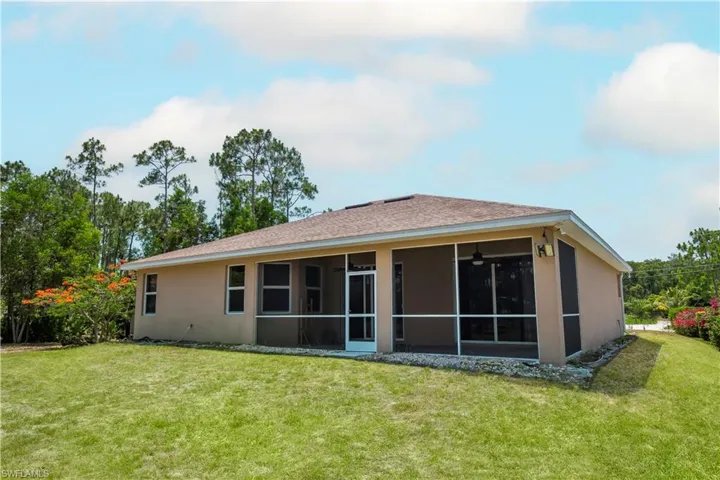 Back of house with a covered lanai and a lawn