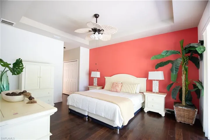 Bedroom featuring ceiling fan, a tray ceiling, and dark hardwood / wood-style floors