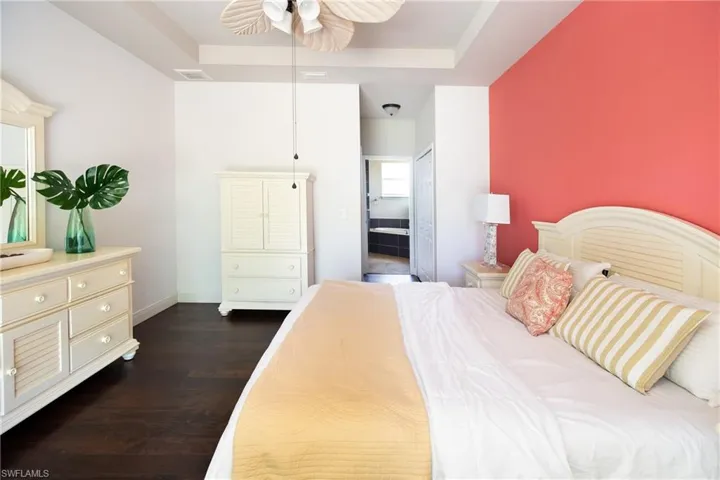 Bedroom with a tray ceiling, ceiling fan, and dark hardwood flooring