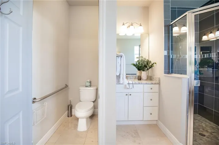 Bathroom featuring walk in shower, tile flooring, vanity, and toilet