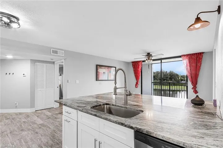 Kitchen featuring white cabinets, dishwasher, dark stone counters, and ceiling fan