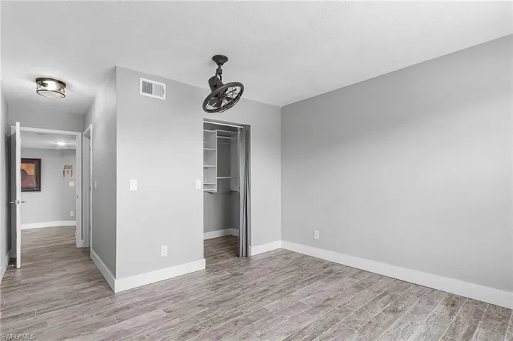 Unfurnished bedroom featuring a spacious closet, light wood-type flooring, and a textured ceiling