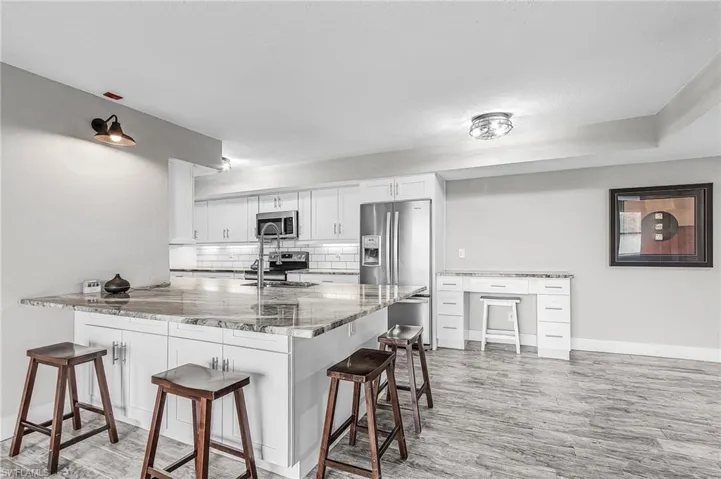 Kitchen featuring a breakfast bar, a peninsula, decorative backsplash, and light stone counters