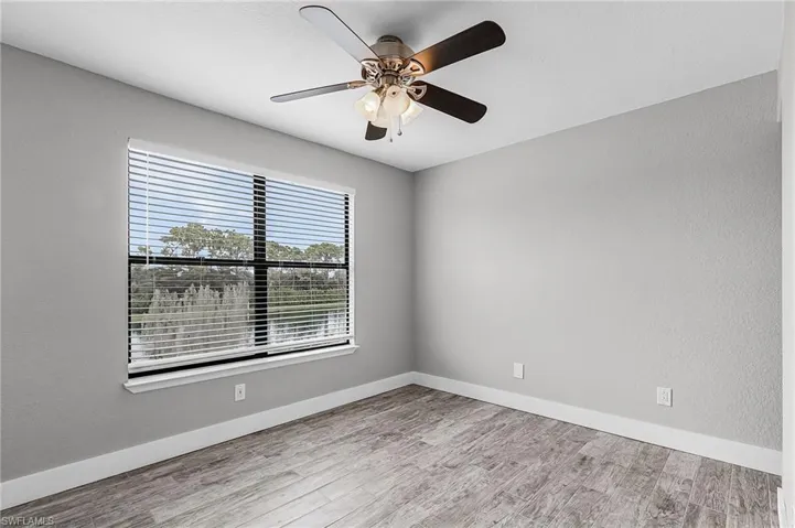 Empty room featuring light wood finished floors, ceiling fan, and a textured wall