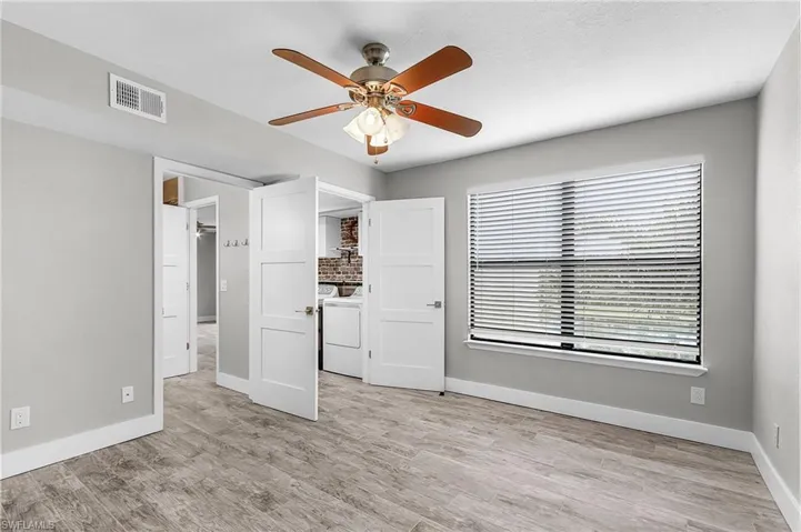 Unfurnished bedroom featuring ceiling fan, light wood-type flooring, and washer / clothes dryer