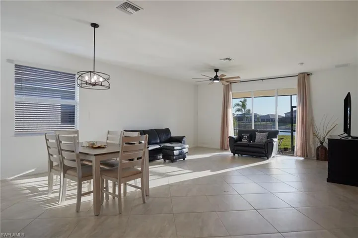 Dining space featuring a ceiling fan, light tile patterned floors, and a chandelier