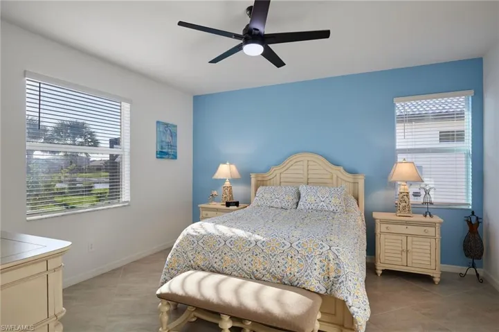 Primary bedroom featuring a ceiling fan, multiple windows, and light tile patterned floors