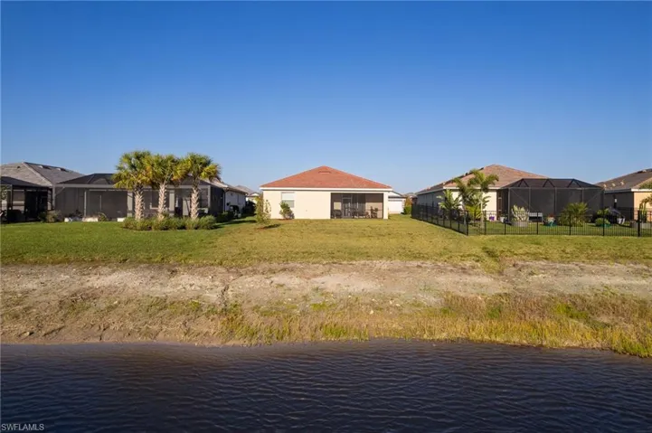 Back of house with a sunroom, a water view, a residential view, and glass enclosure