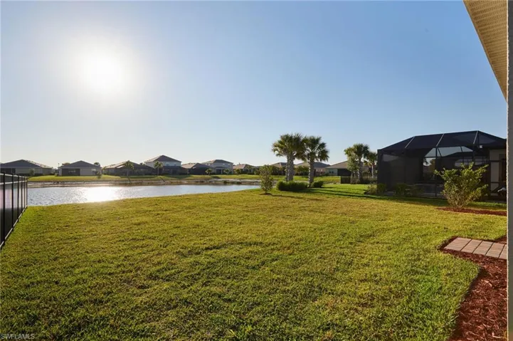 View of grassy yard with a sunroom, a residential view, a water view, and a lanai