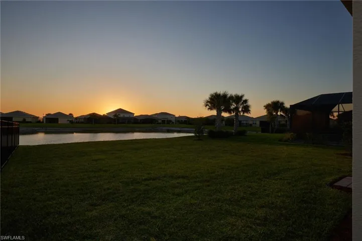 View of green lawn with a residential view and a water view