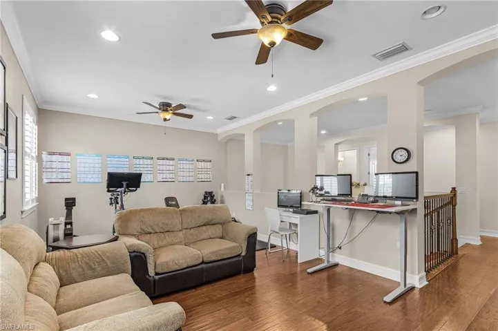 Living room featuring a ceiling fan, a desk, wood finished floors, recessed lighting, and arched walkways