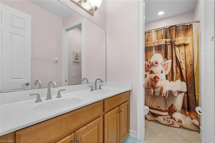 Full bathroom with double vanity, tile patterned floors, and a shower with curtain