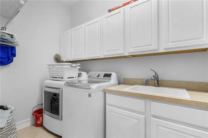 Washroom with independent washer and dryer, cabinet space, and light tile patterned floors