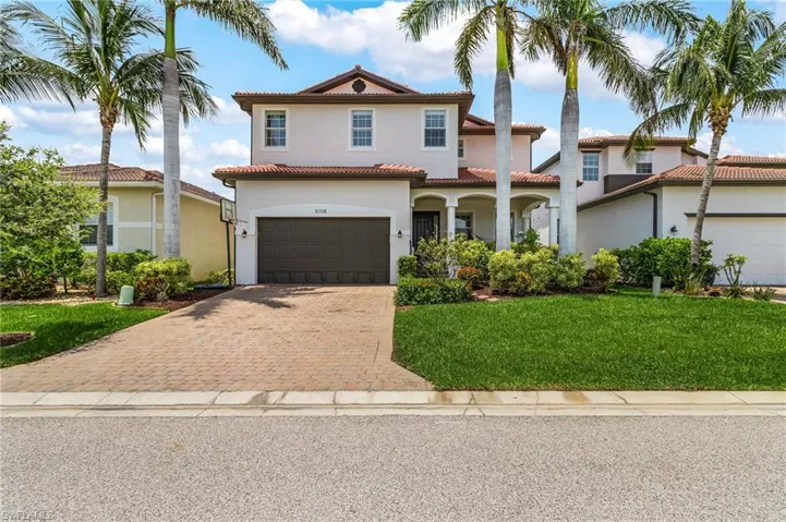 Mediterranean / spanish-style home with decorative driveway, stucco siding, a tiled roof, an attached garage, and a front lawn